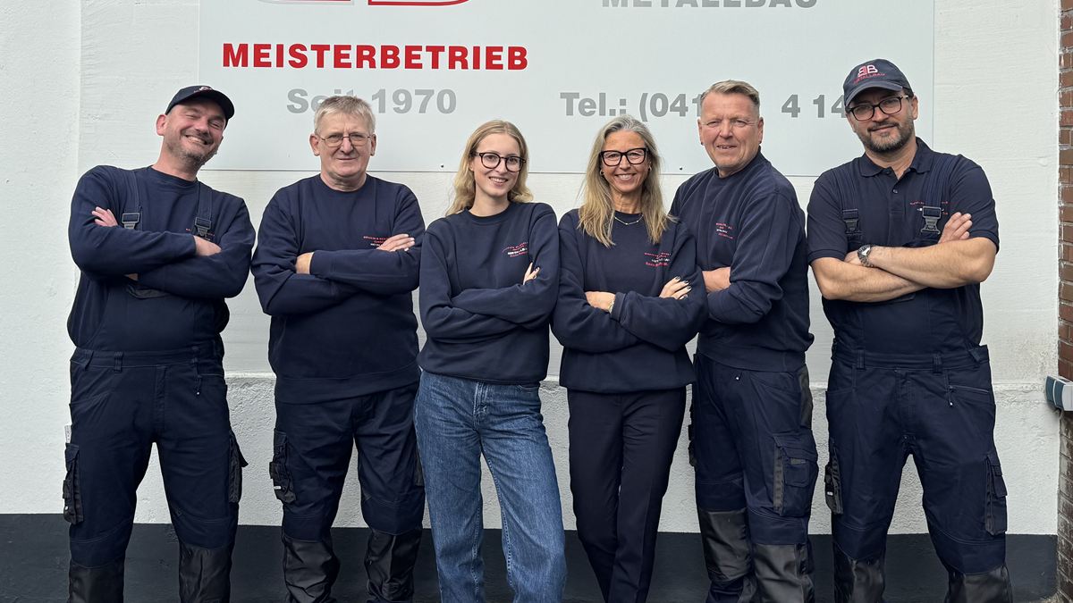 Das Team der Bruhn & Beilfuss GmbH mit verschränkten Armen vor dem Firmenschild